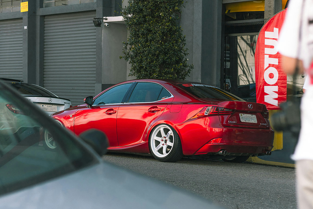 Side profile of a silver Lexus IS 300 luxury sedan parked on a modern city street, highlighting its aerodynamic lines and alloy wheels.